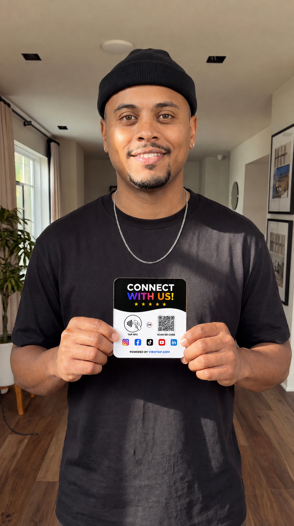 Man holding a Viro Tap Connect With Us NFC sign at home